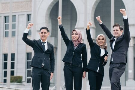 Group of young executive people in formalwear holding tablet with happy face expression and hand risingの写真素材