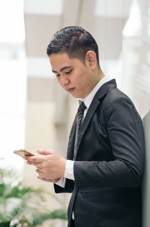 Portrait of young businessman Texting to Someone on his Mobile Phone with Happy Facial Expression.の写真素材