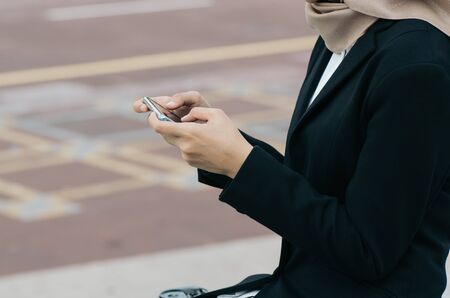 unidentified businesswoman in elegant suit sitting and SMS or  text messages with her mobile phone appの写真素材