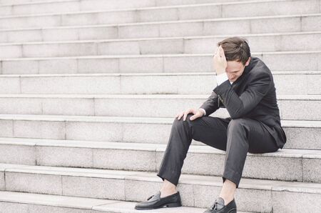 frustrated and depressed expression face,young business man sitting on stairsの写真素材