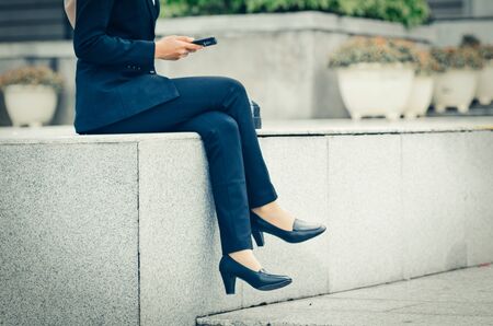 unidentified business woman sitting while sms her friend during lunch hourの写真素材