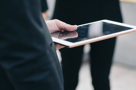 unidentified businesswoman in elegant suit sitting holding mobile tabletの写真素材