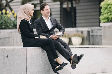 young business couple in formalwear siiting outside and having discussionの写真素材