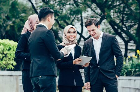 Group of young executive people in formalwear holding tablet and discussing something.happy face expressionの写真素材