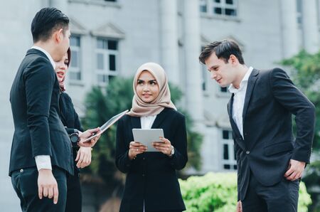 Group of young executive people in formalwear holding tablet and discussing somethingの写真素材