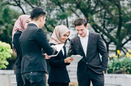 Group of young executive people in formalwear holding tablet and discussing something.happy face expressionの写真素材