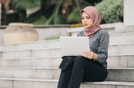 confident expression,  young executive business woman sitting on stars and work with her laptop.focus on laptopの写真素材