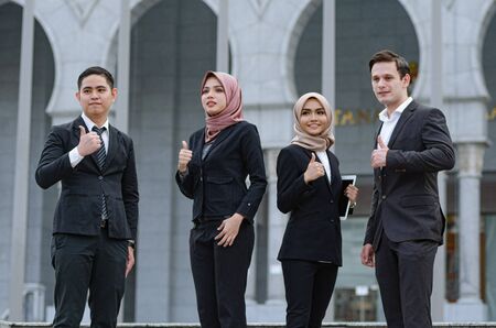 Portrait group of young executive, dressed in formal wear giving thumbs-upの写真素材