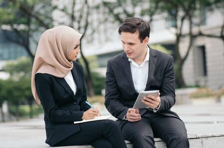 young business couple in formalwear siiting outside and having discussionの写真素材