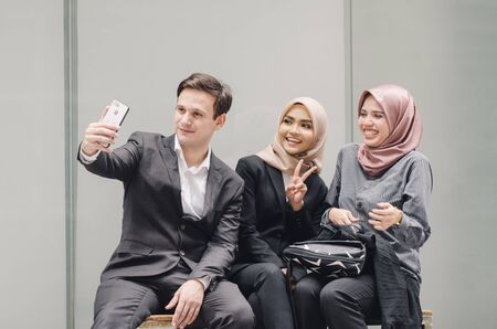 happy face expression, group of young businesswoman and businessman in black suit using a mobile phone and taking photoの写真素材