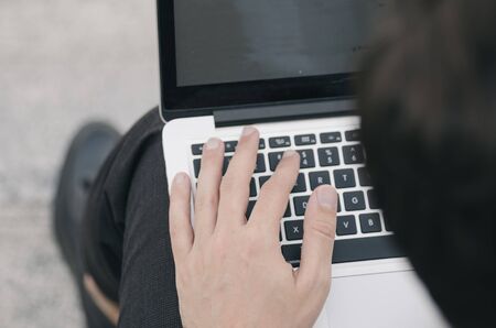 cropped image of hands using laptop with blank white screenの写真素材