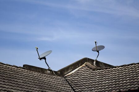 satellite dish antenna installed on roof top over blue sky backgroundの写真素材