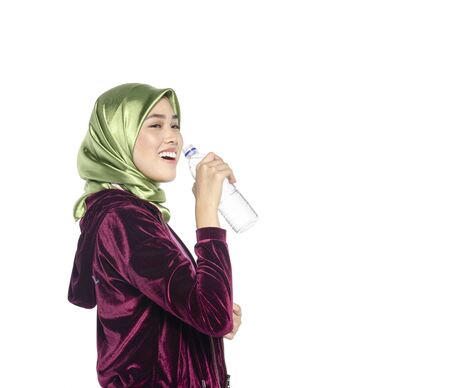 Portrait of a active healthy hijab woman drinking plain water in bottle for promoting a healthy fitness and lifestyle conceptの写真素材