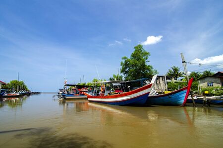 Beautiful rural scenery, fisherman boat moored near wooden jetty over blue sky backgroundの写真素材