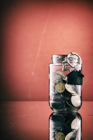coin in transparent glass jar over red background for financial concept