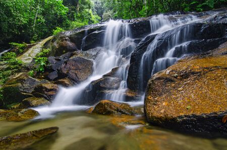 Beautiful tropical waterfall in lush surrounded by green forest.wet rock and moss.selective focus shot.の写真素材