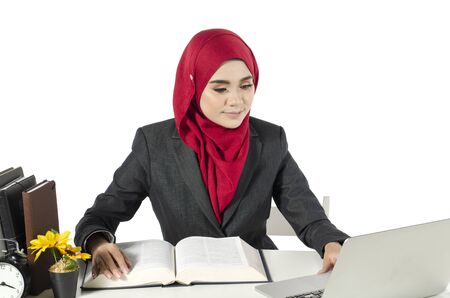 young businesswomen or student in hijab sitting and look at her laptop against white backgroundの写真素材