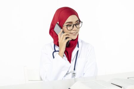 Smile face young doctor with hijab used her handphone for calling her friendsの写真素材