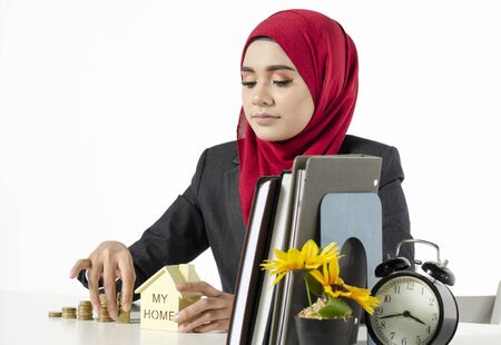 young woman with hijab savings money for her new home against white backgroundの写真素材