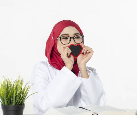 Medical and healthcare concept, confident young doctor sitting with smile face holding heart symbolの写真素材