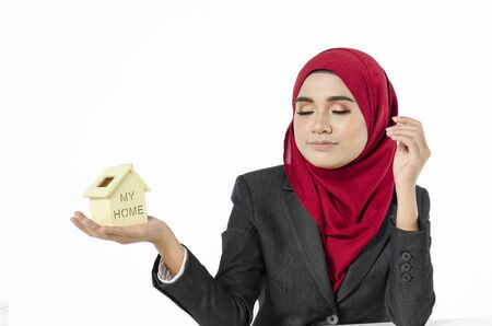 young woman in hijab holding home replica, closed her eye and imagine dream houseの写真素材