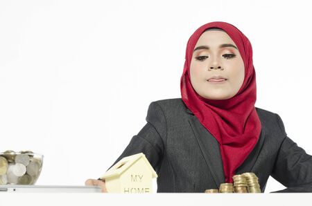 young woman with hijab savings money for her new home against white backgroundの写真素材