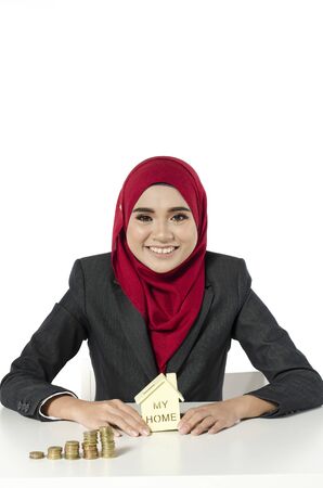 young woman with hijab savings money for her new home against white backgroundの写真素材
