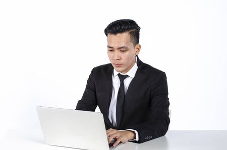 young handsome businessman sitting and working with his laptop over white backgroundの写真素材