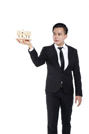 Real estate agent standing and holding home replica against white backgroundの写真素材