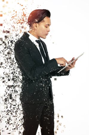 Communication concept, young man standing and texting her friends using his handphone against white backgroundの写真素材