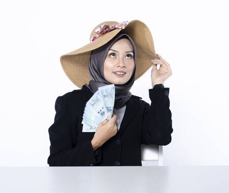 Portrait of satisfied young businesswoman in hijab looks with desire on money