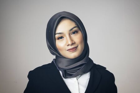 young confident bsinesswoman with hijab in suit standing over dark backgroundの写真素材