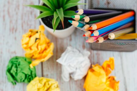 Back to school and offices stationary concept, stack of colored pens marker In a metal case, crumple paper and artificial plant on wooden deskの写真素材