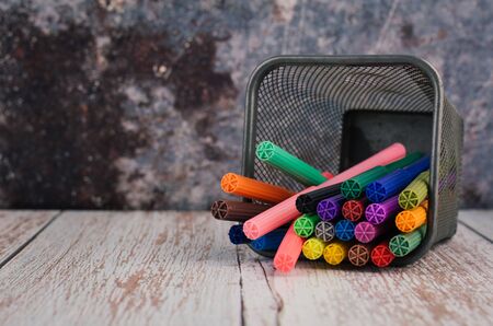 Back to school and offices stationary concept, stack of colored pens markers In a metal case over dark backgroundの写真素材