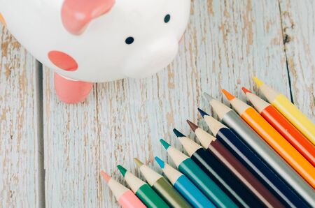 saving for education or back to school concept, piggy bank and colorful marker pen on wooden desk.の写真素材