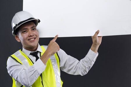 happy face young engineer or manager with white safety helmet holding white board.の写真素材