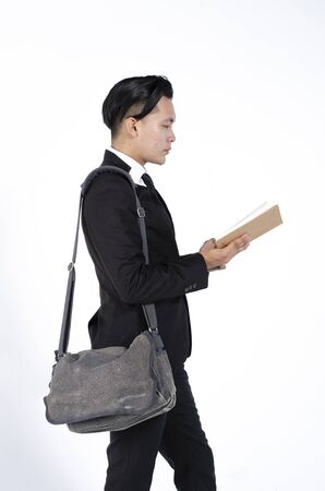 Portrait of young college student in black suit with books and backpack against white backgroundの写真素材