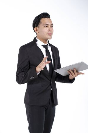 Young business man wearing black suit holding tablet against white backgroundの写真素材