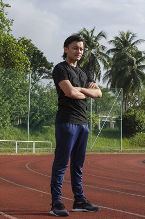 young man runner doing stretching exercise, preparing for morning workoutの写真素材