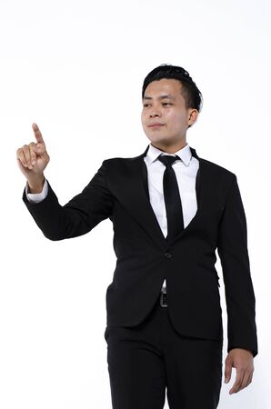 Young business man wearing black suit using finger on augmented reality touch screen against white backgroundの写真素材