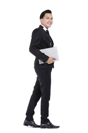 Young business man wearing black suit holding tablet against white backgroundの写真素材