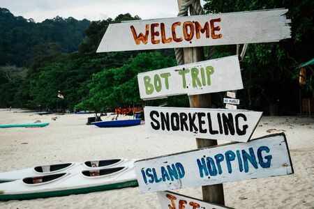 pieces of wood with hand painted beach activities attached to tree stump in Pangkor Island, Perak State, Malaysiaの写真素材