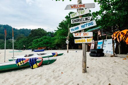 pieces of wood with hand painted beach activities attached to tree stump in Pangkor Island, Perak State, Malaysiaの写真素材