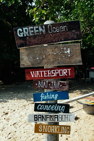 pieces of wood with hand painted beach activities attached to tree stump in Pangkor Island, Perak State, Malaysiaの写真素材