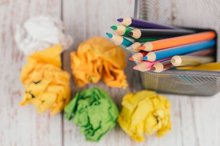 Back to school and offices stationary concept, stack of colored pens marker In a metal case and crumple paper on wooden deskの写真素材