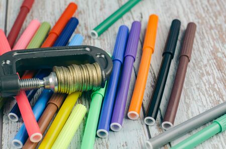 struggle saving for education concept, stacking coin squeezing in a G-clamp, and colorful marker pen on wooden desk.の写真素材