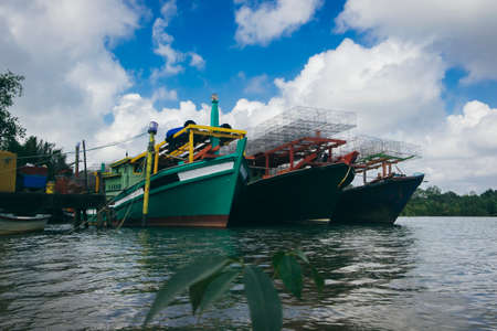 Beautiful view at Traditional fishing village with lovely sky and fishing boat moored near the shoreの写真素材