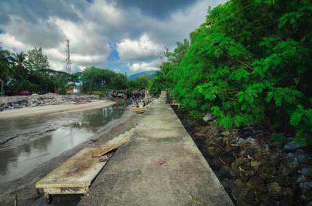 Concrete jetty for local fisherman during low tide water againts cloudy sky backgroundの写真素材