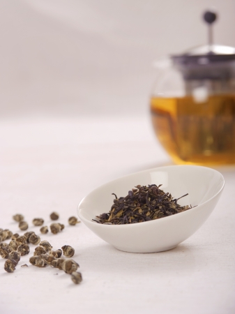 Selective focus of tea leaves in white bowl with teapot in white backgroundの写真素材