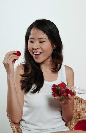 Asian girl happy, eating strawberryの写真素材